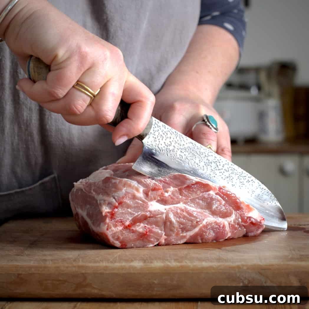 Slow Cooker Pork in Cider and Mustard Sauce 4 Womans hands slicing a joint of pork with a large silver knife on a wooden chopping board