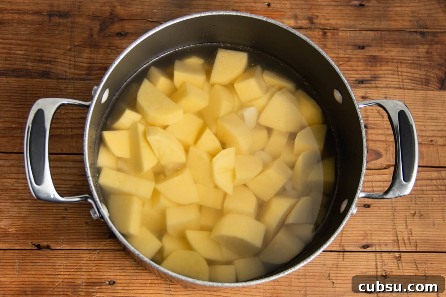 This is a picture of a pot with water and chopped potatoes.