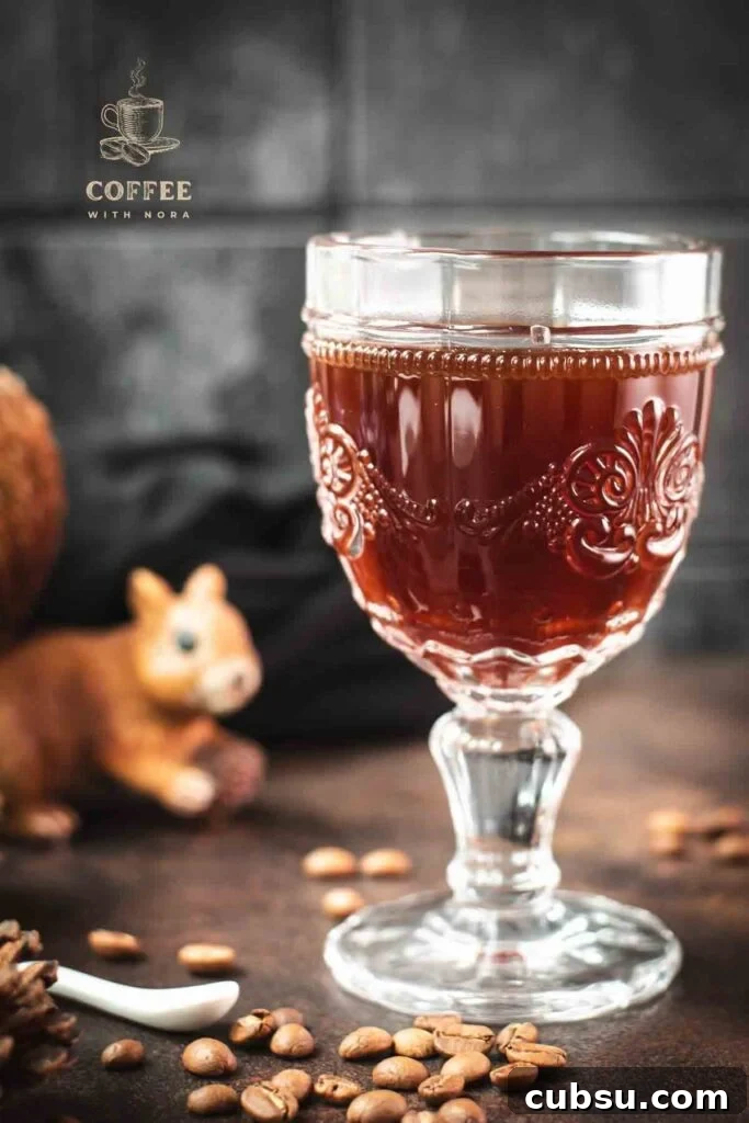Gorgeous glass filled with maple syrup coffee, placed on dark brown ground, next to squirrel figure.