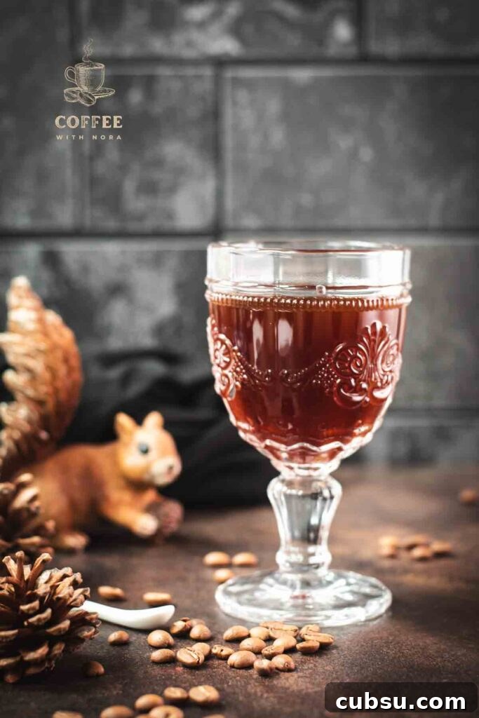 Gorgeous glass filled with maple syrup coffee, placed on dark brown ground, next to squirrel figure.