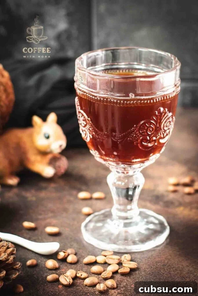 Gorgeous glass filled with maple syrup coffee, placed on dark brown ground, next to squirrel figure.