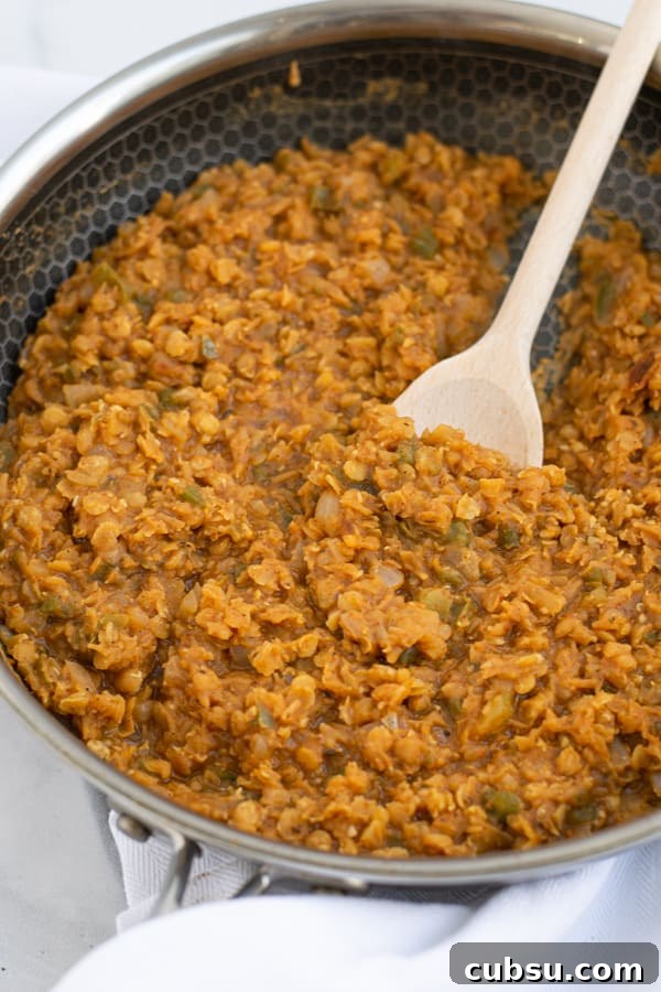 red lentil taco 'meat' in a large frying pan with a spoon