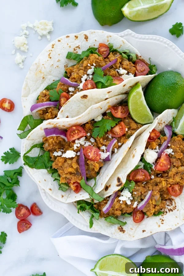 three red lentil tacos sit-in non a white plate with colorful garnishes
