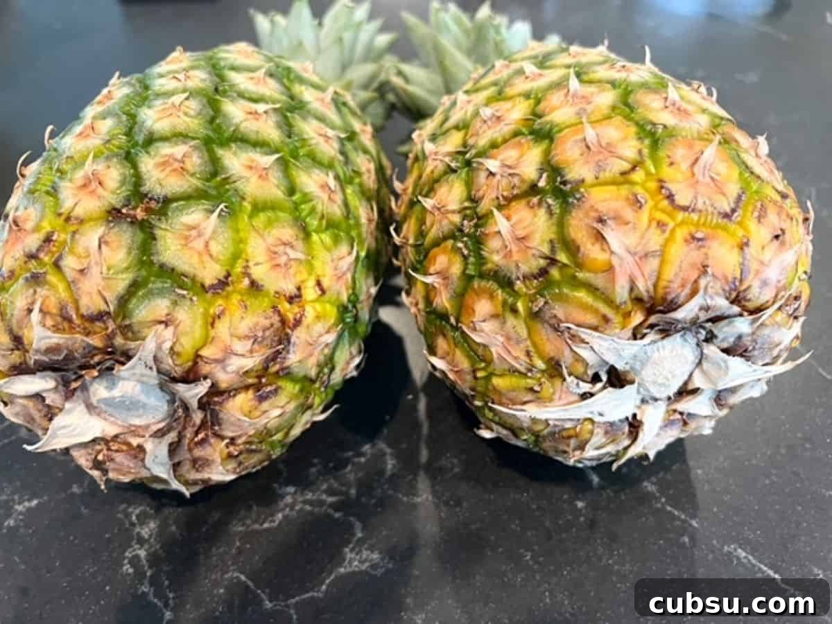 How to Choose a Ripe, Sweet Pineapple: Expert Tips for Picking One 3 Two ripe pineapples laying on their sides next to each other.