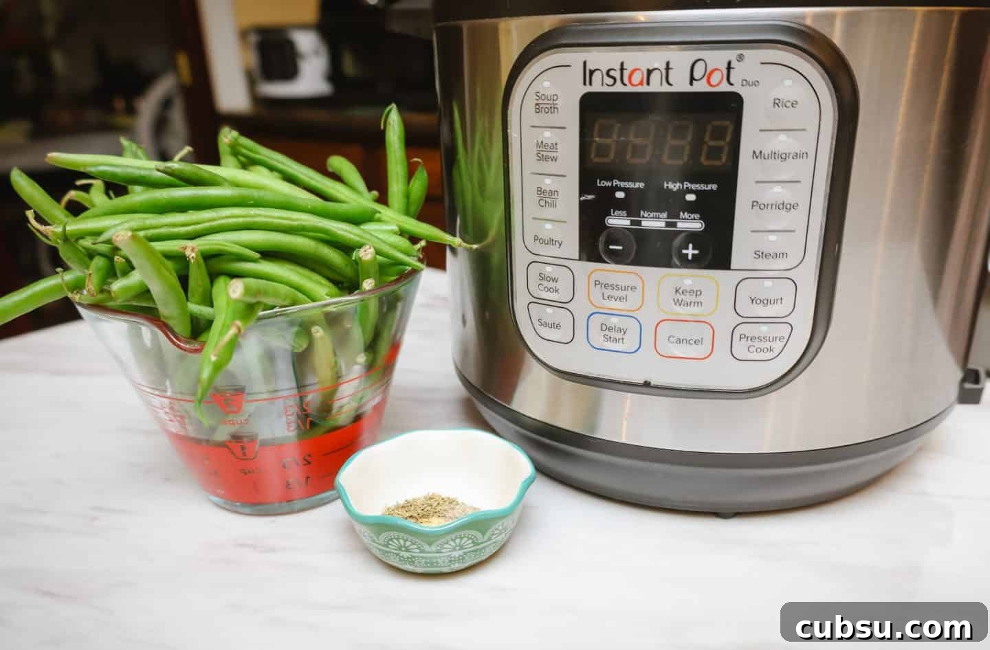 Fresh green beans measured beside an Instant Pot with thyme and seasoning, demonstrating how to cook Southern soul food green beans in a pressure cooker.