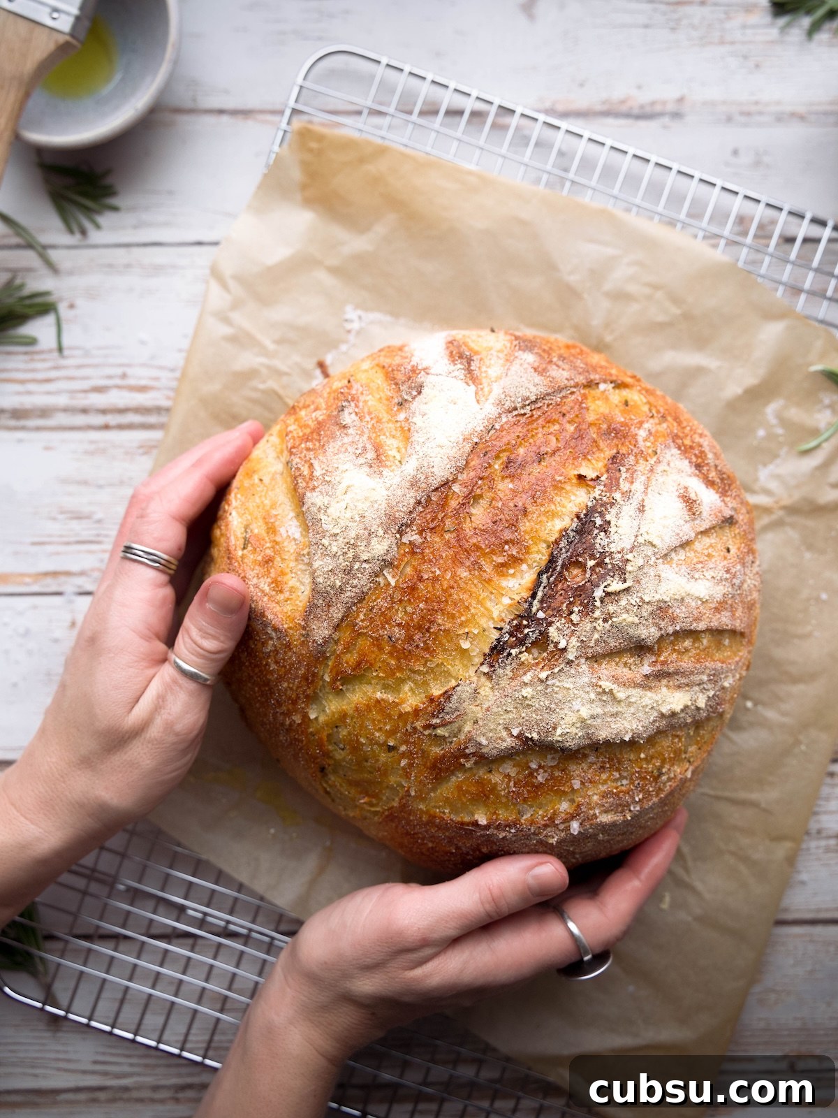 Rosemary Sea Salt Sourdough Bread Recipe for Crispy Crust 2 Hands holding a homemade sourdough boule