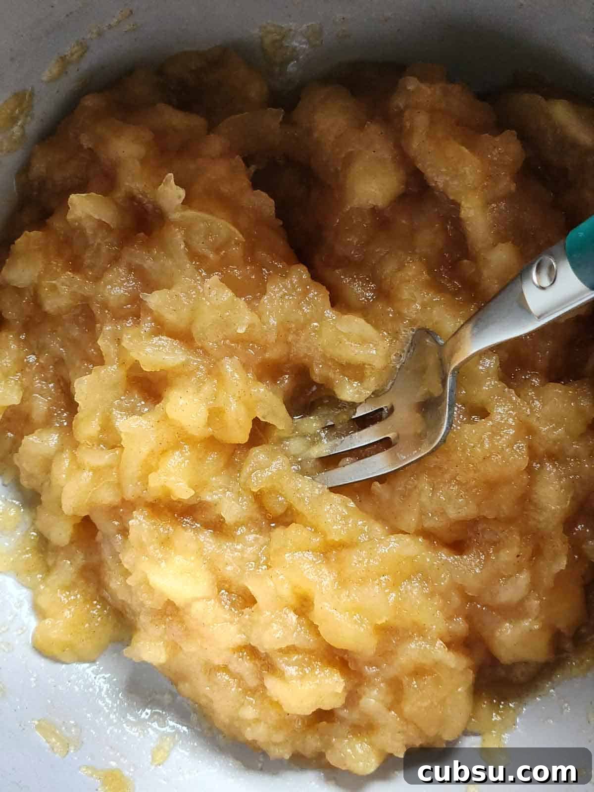 A fork in a pot after mashing apples for applesauce.
