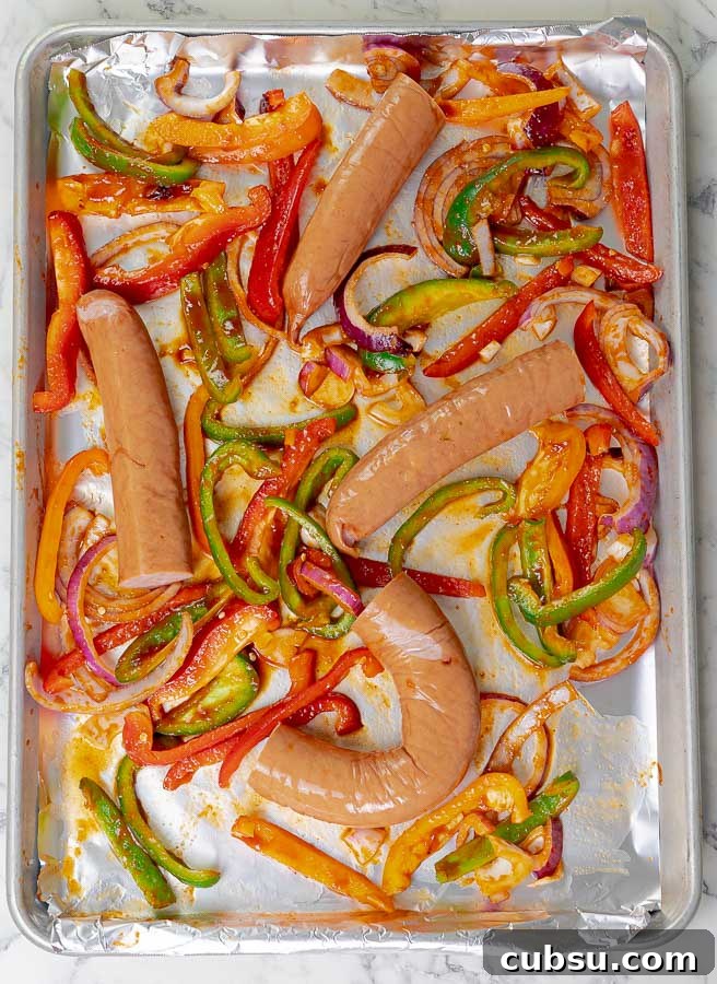 sausages and peppers on baking sheet ready to be cooked
