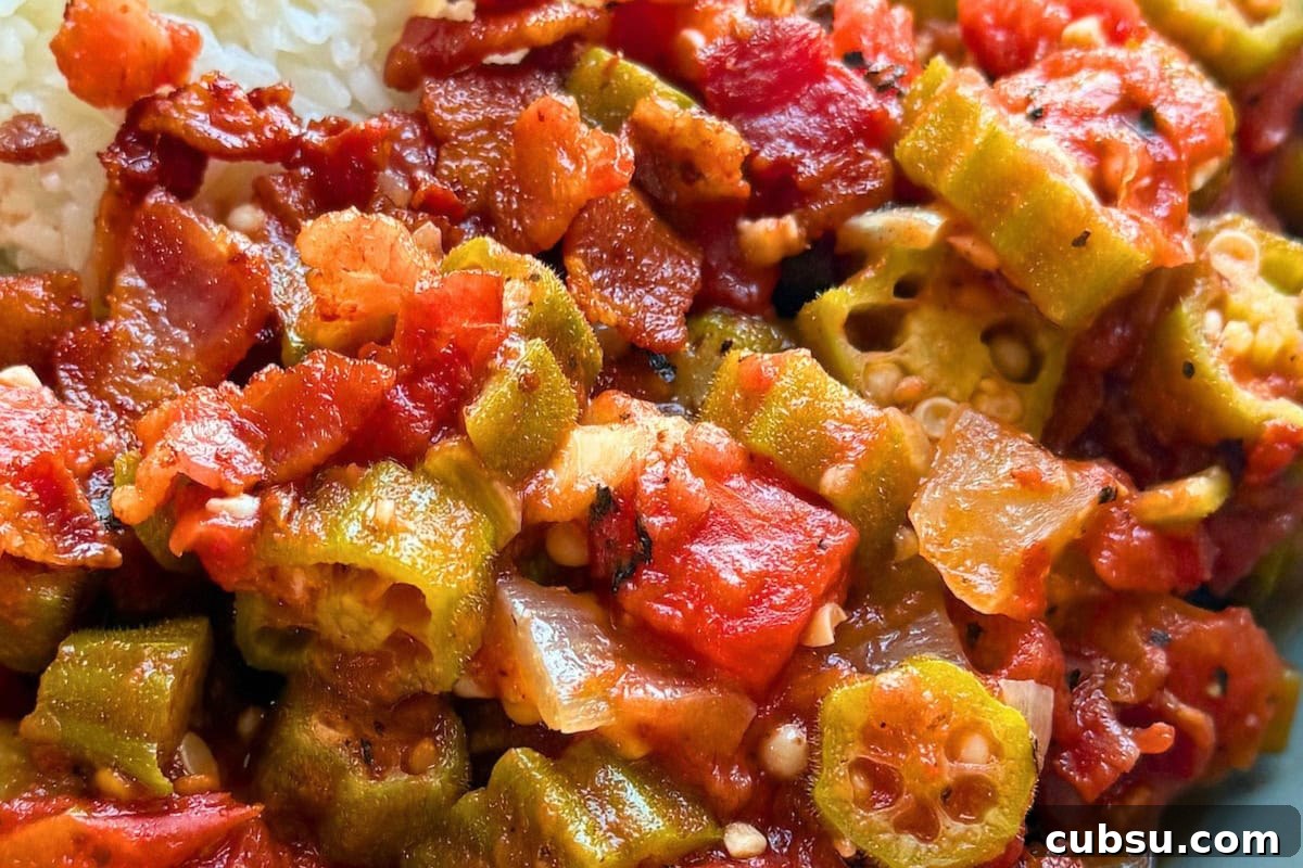 8 Must-Try Okra Recipes to Savor Before Summer Ends 2 A close-up of a flavorful Southern-style dish featuring sautéed okra, tomatoes, and crispy bacon, served alongside a portion of rice.