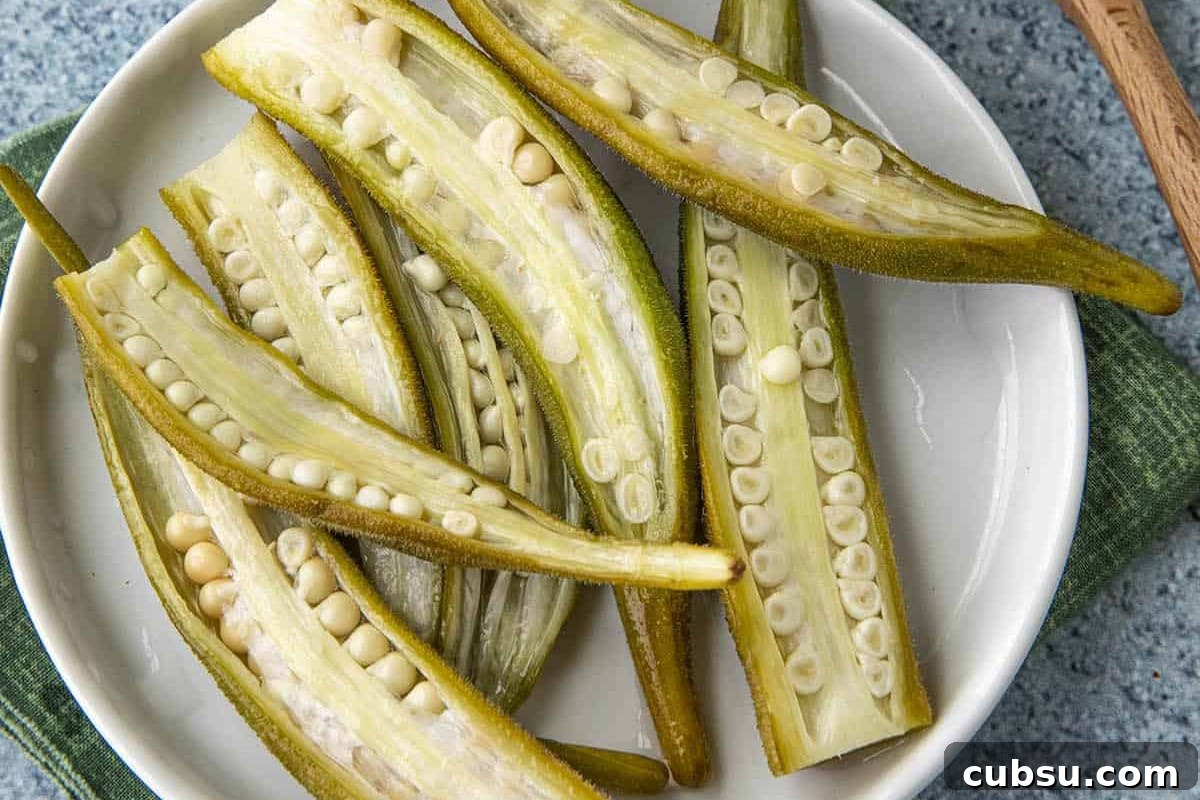8 Must-Try Okra Recipes to Savor Before Summer Ends 7 A close-up of freshly cut okra halves displayed on a white plate, showcasing their interior filled with small seeds.
