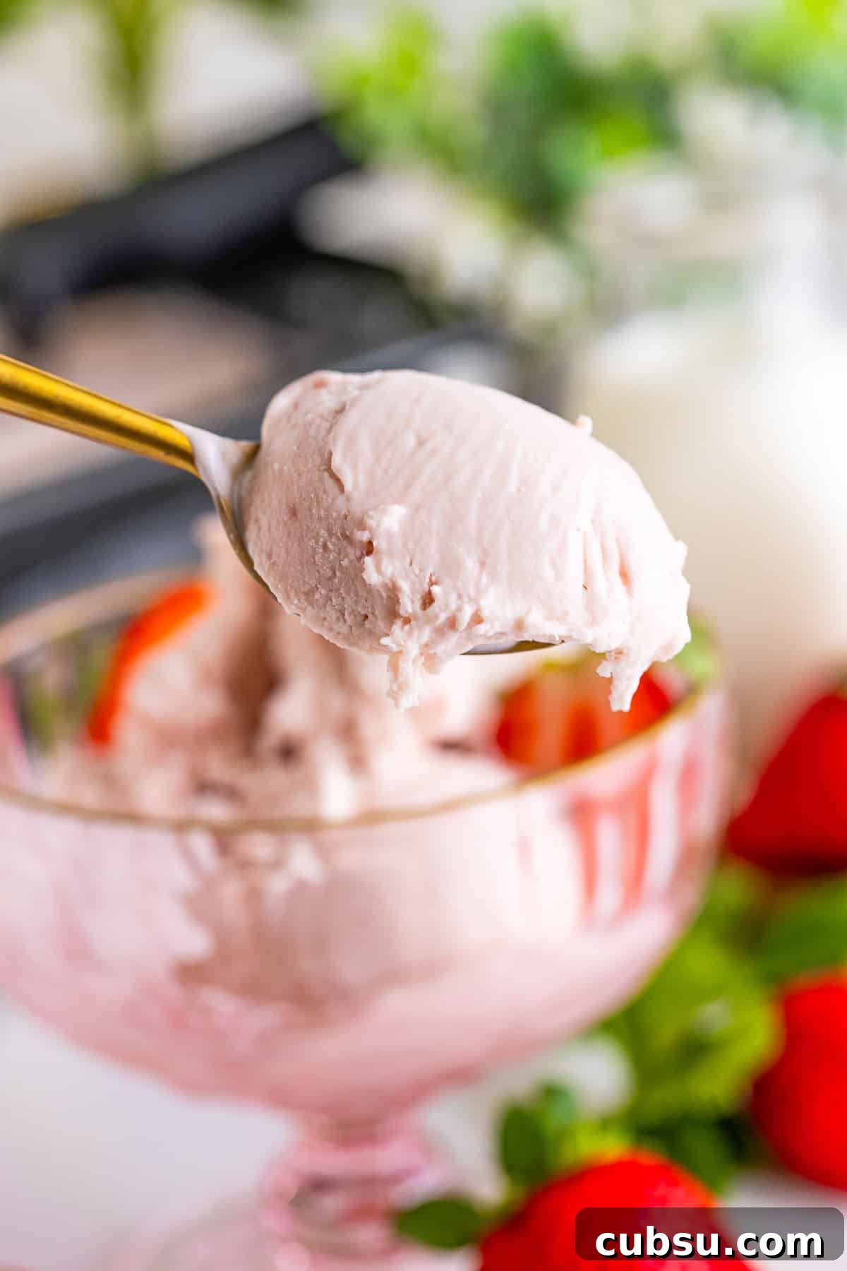 a spoon holding up a bite of Strawberry ice cream in air