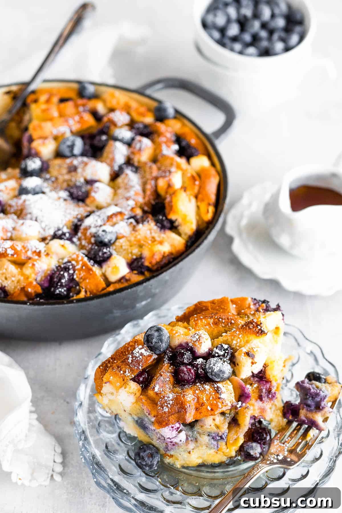 A Serving of Blueberry French Toast Bake on a Plate with the Full Casserole Behind it
