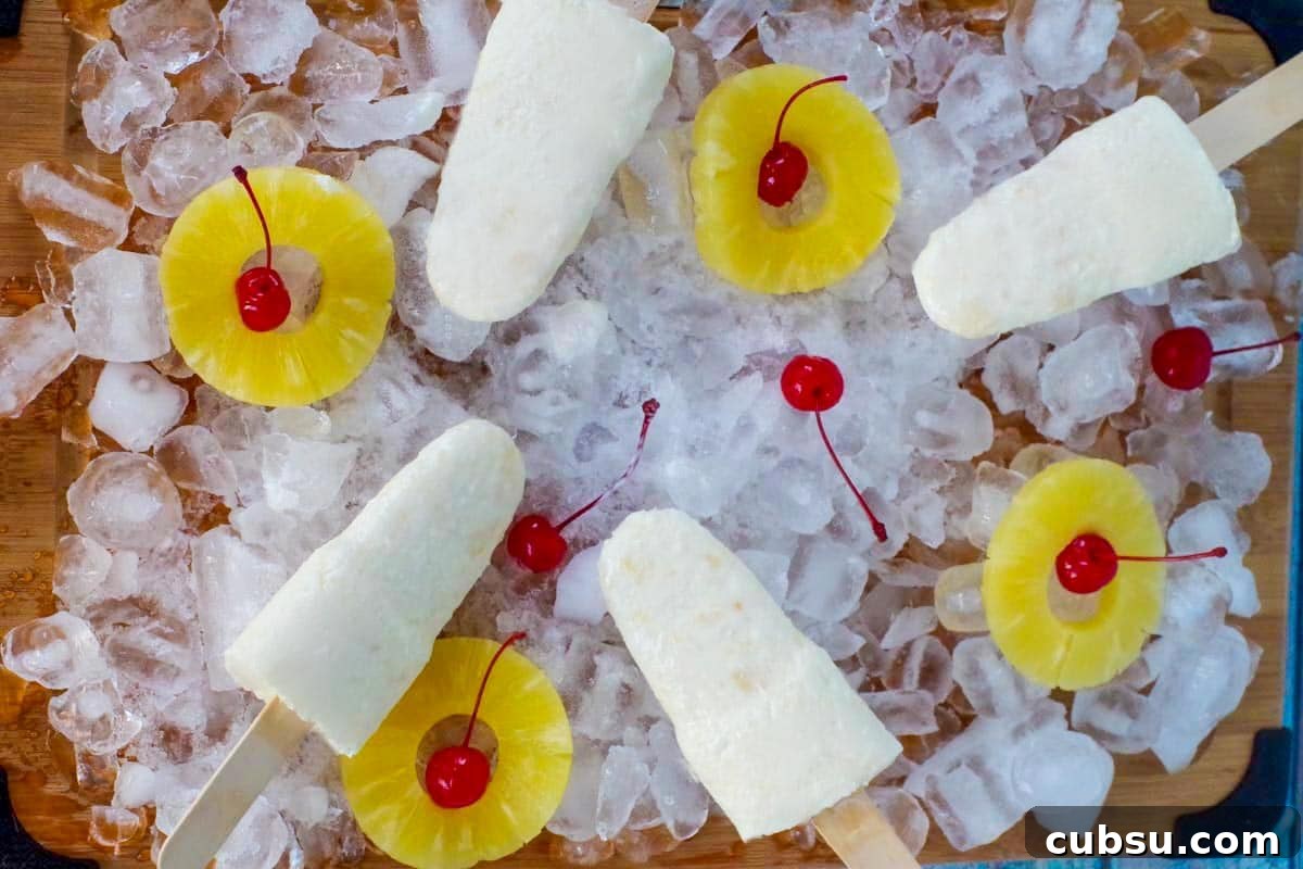 pina colada popsicles on a bed of ice with pineapple and cherries
