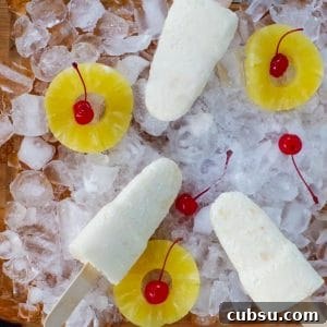 pina colada popsicles on a bed of ice with pineapple and cherries