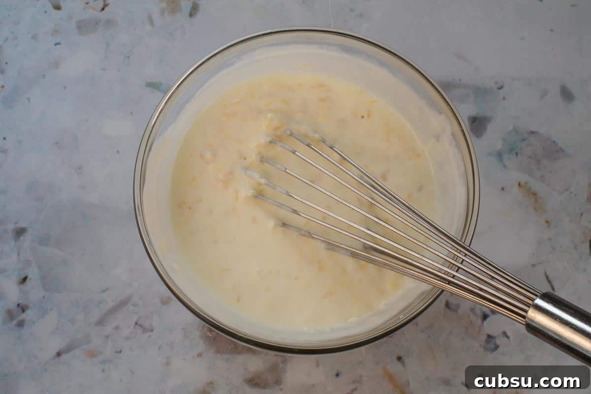 All ingredients in a large glass bowl being whisked together.