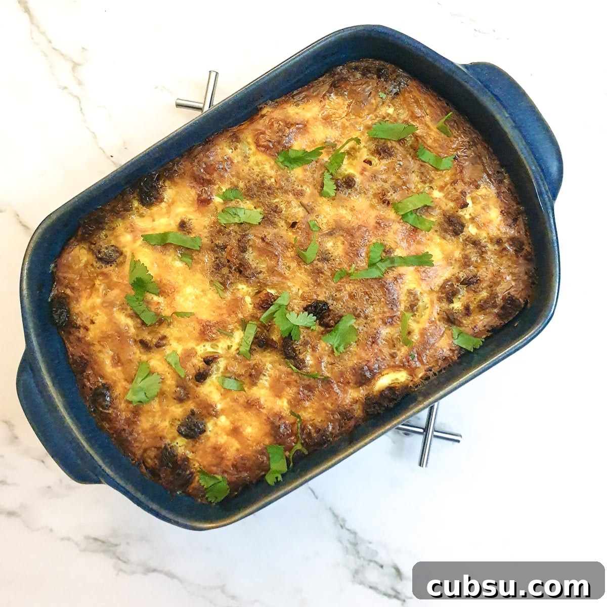 The completed dish of bobotie garnished with coriander.