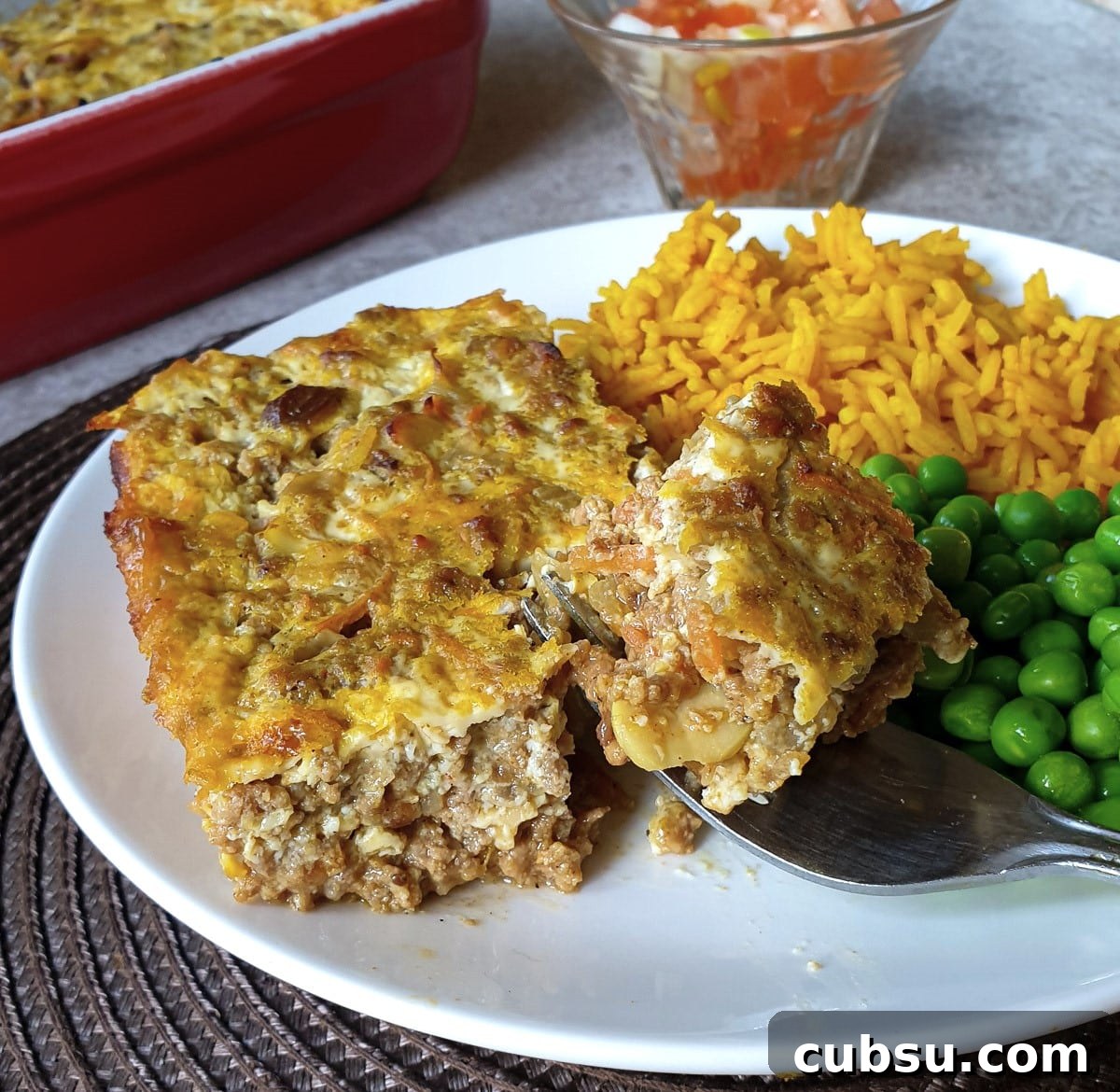 Closeup of a helping of bobotie with yellow rice and peas.