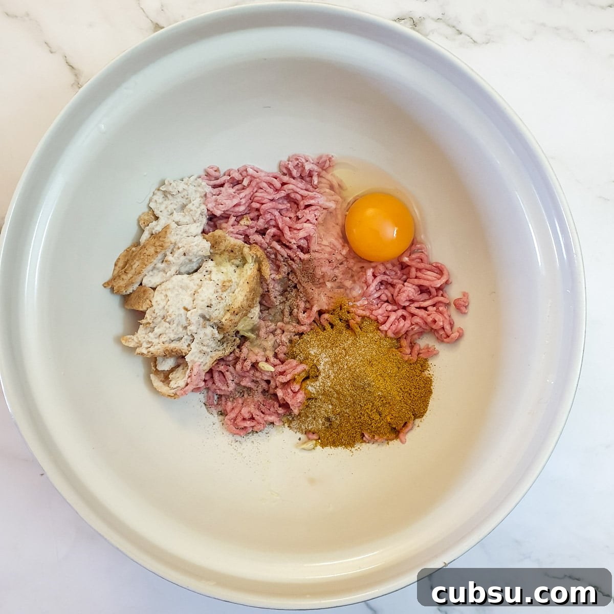 Ground meat, egg and spices in a mixing bowl.