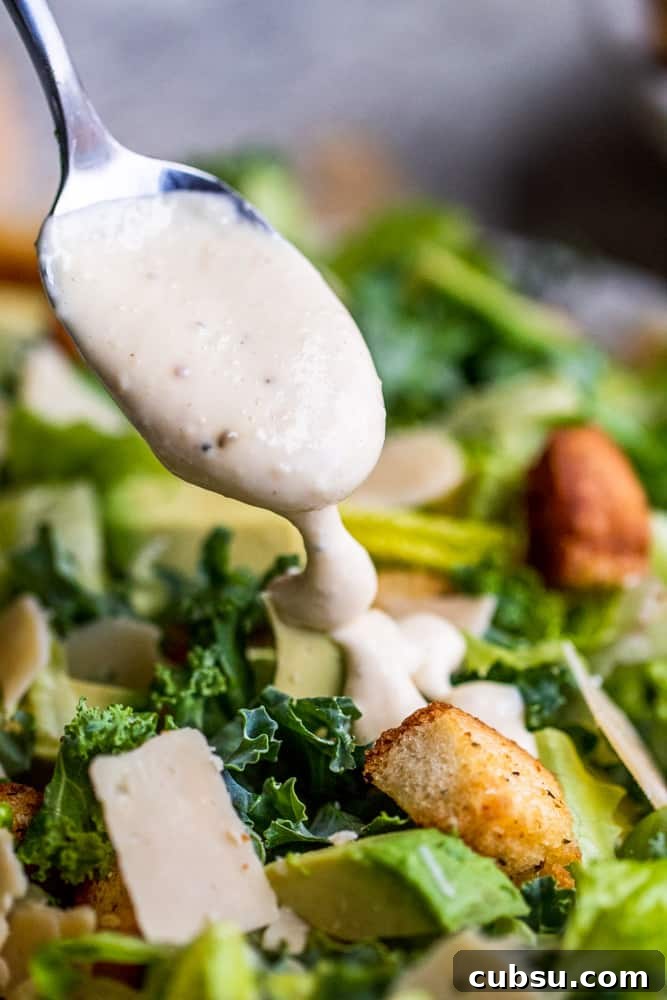 Drizzle dressing over the salad. Silver spoon drizzling dressing over salad.