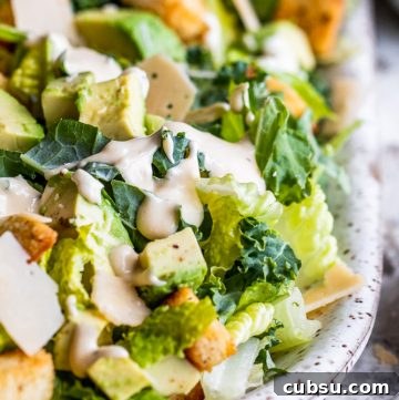 Creamy Kale Caesar Salad with Avocado Slices 3 Kale salad on a white plate.