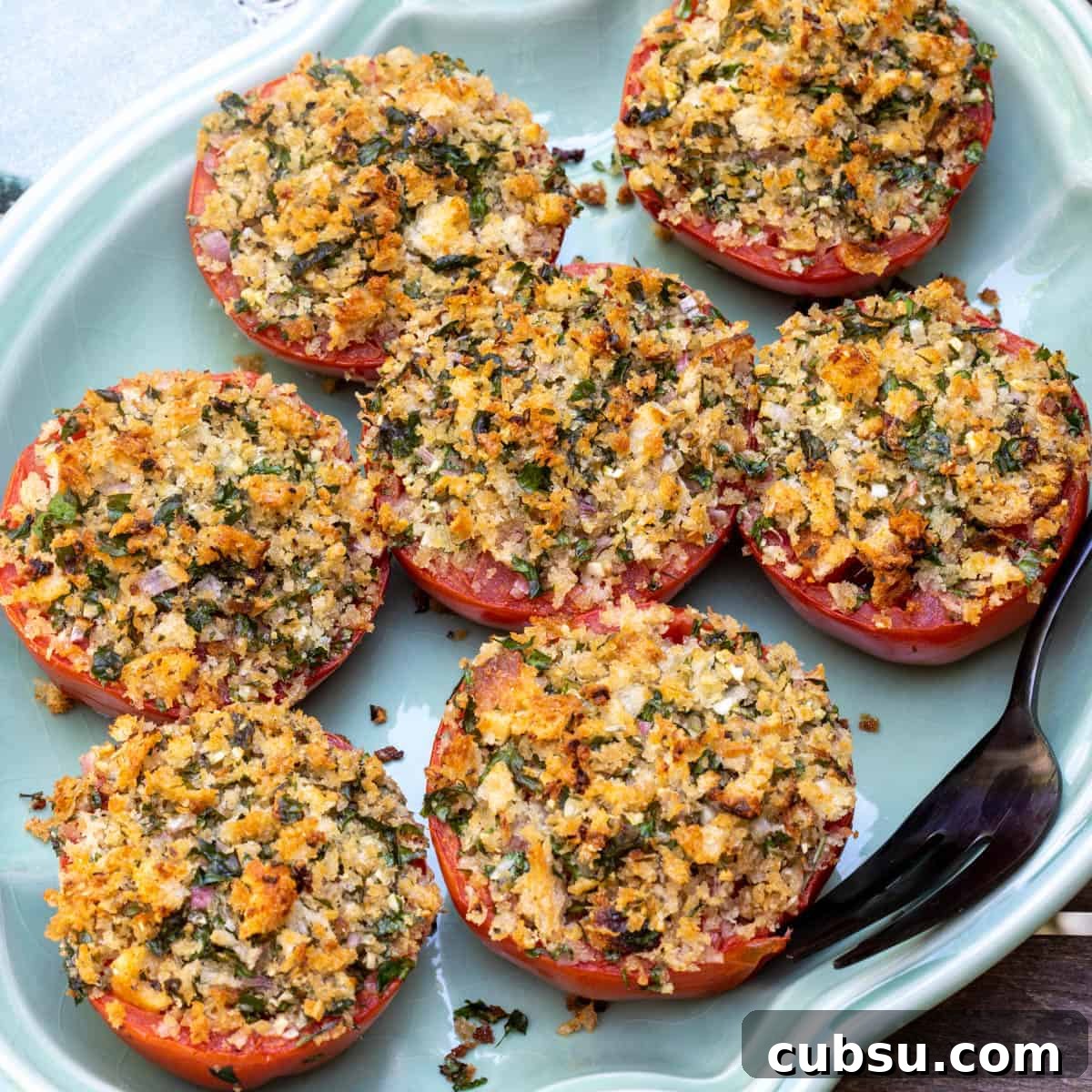 close up of tomatoes provencal on light green platter with serving fork