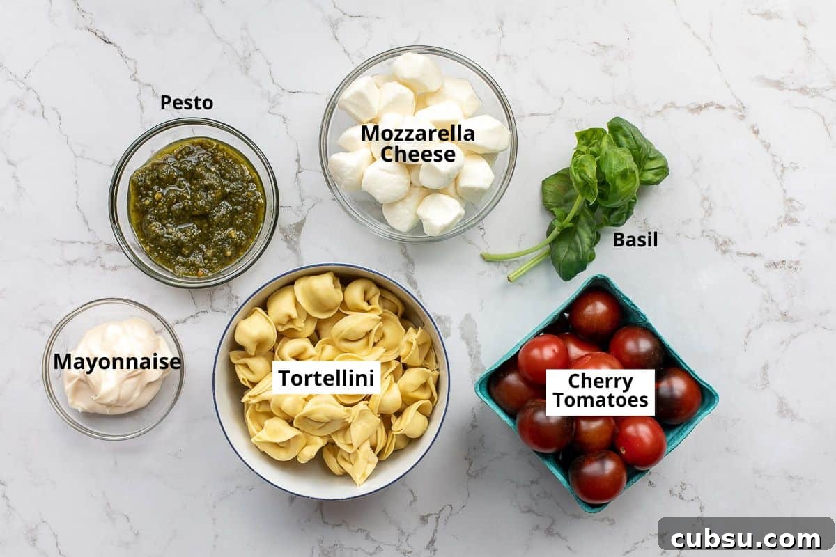 bowls of tortellini, mayonnaise, pesto, mozzarella cheese, basil, and cherry tomatoes