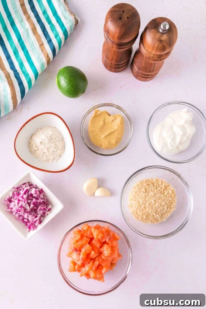 Overhead view of ingredients for salmon burger, including salmon, panko, onion, garlic, mustard, sour cream, and lime