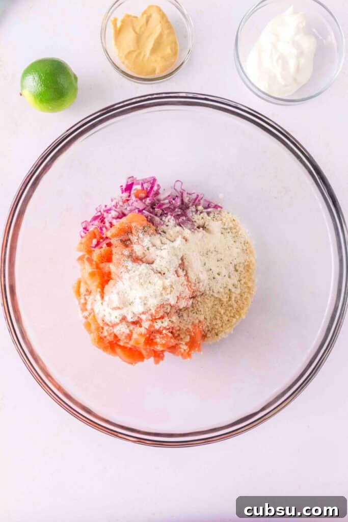 Mixing bowl with chopped salmon, red onion, panko, and ranch seasoning before combining