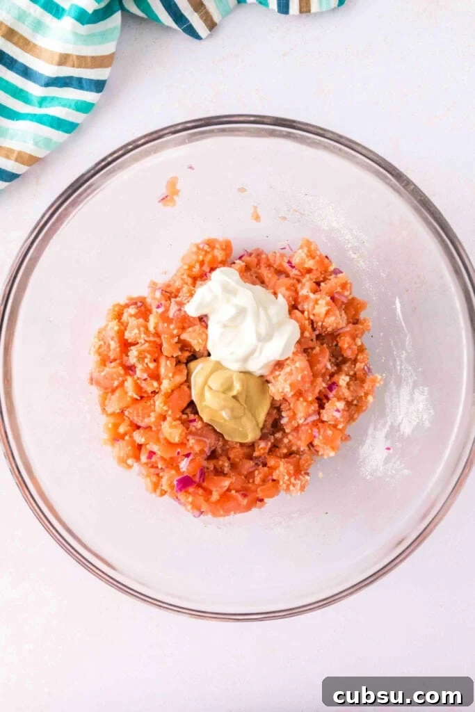 Partially mixed salmon burger mixture with sour cream and mustard added on top