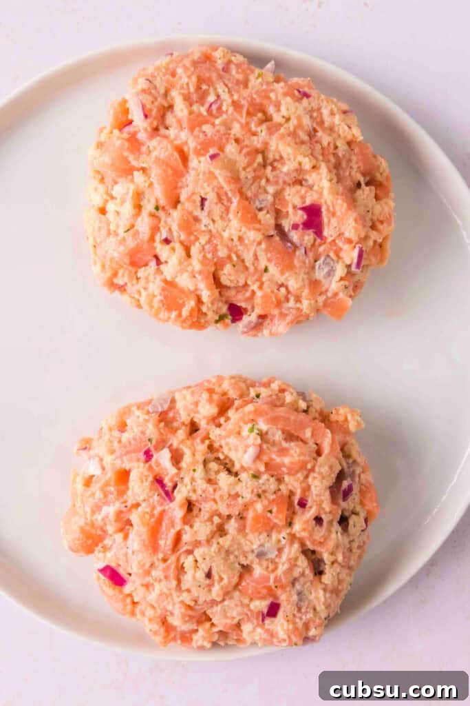 Formed raw salmon burger patties on a plate, ready for grilling