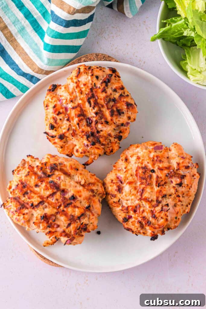 Grilled salmon burger patties resting on a plate with char marks visible