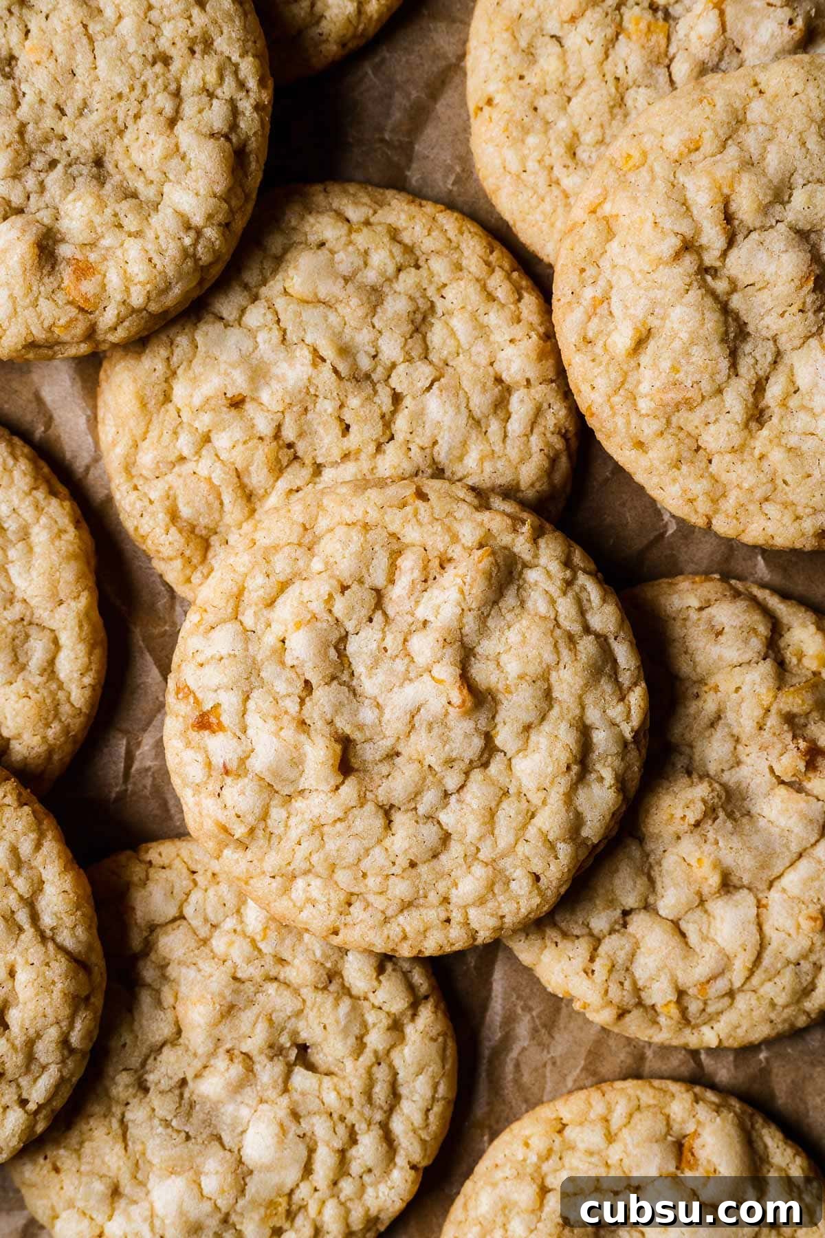 Golden brown cookies piled on brown parchment paper.