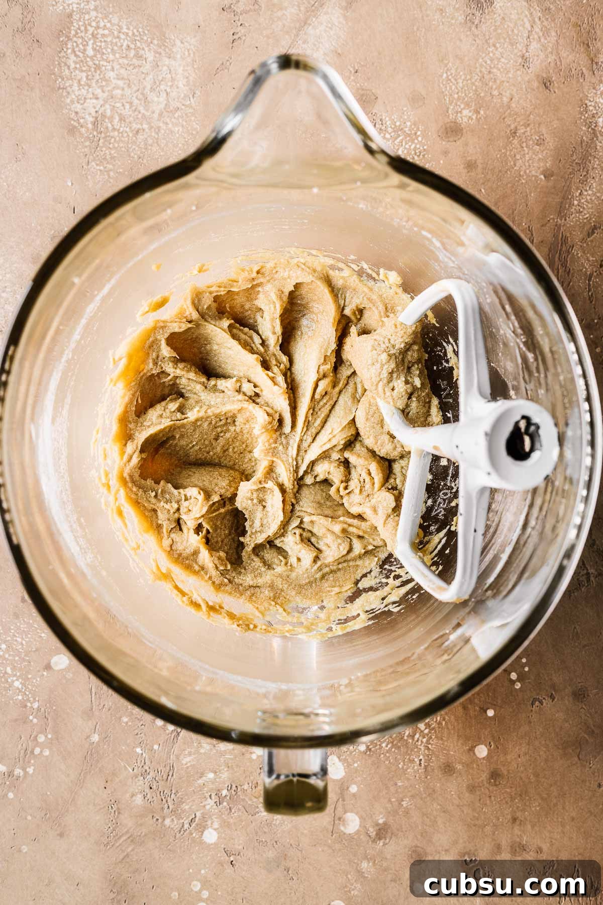Butter, sugar and eggs mixed together in a clear glass bowl.