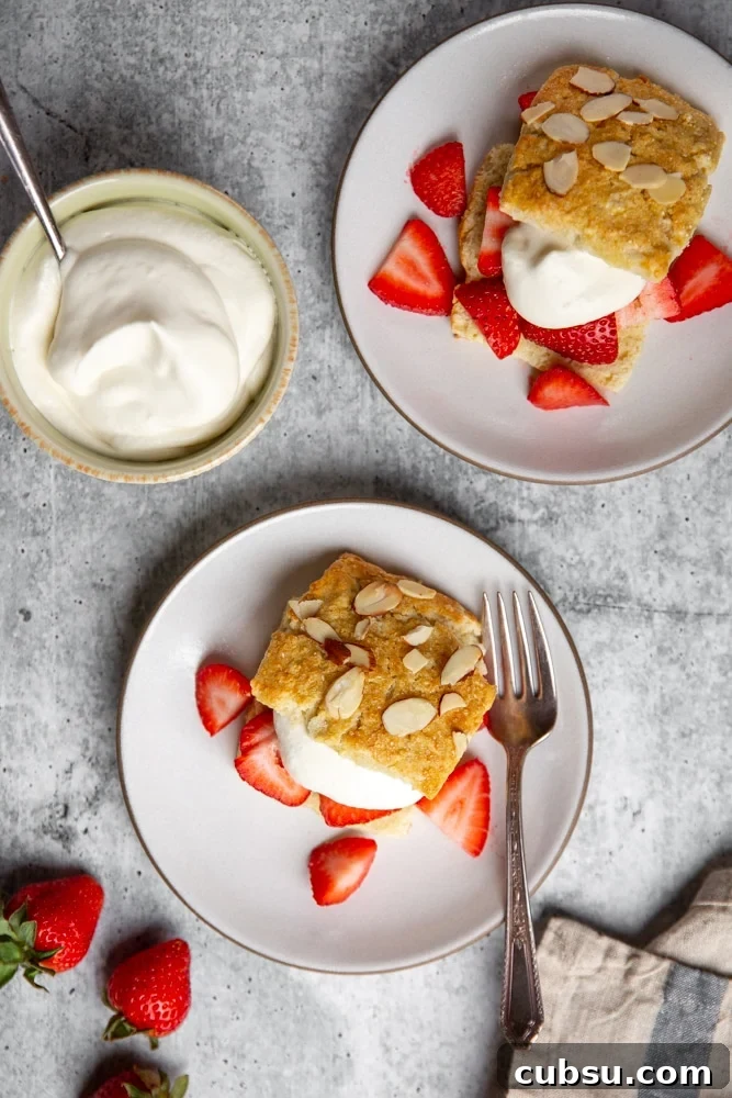 Strawberry shortcakes on plates with a bowl of whipped cream alongside. 