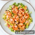 Cajun shrimp salad served in bowls with extra dressing on the side.