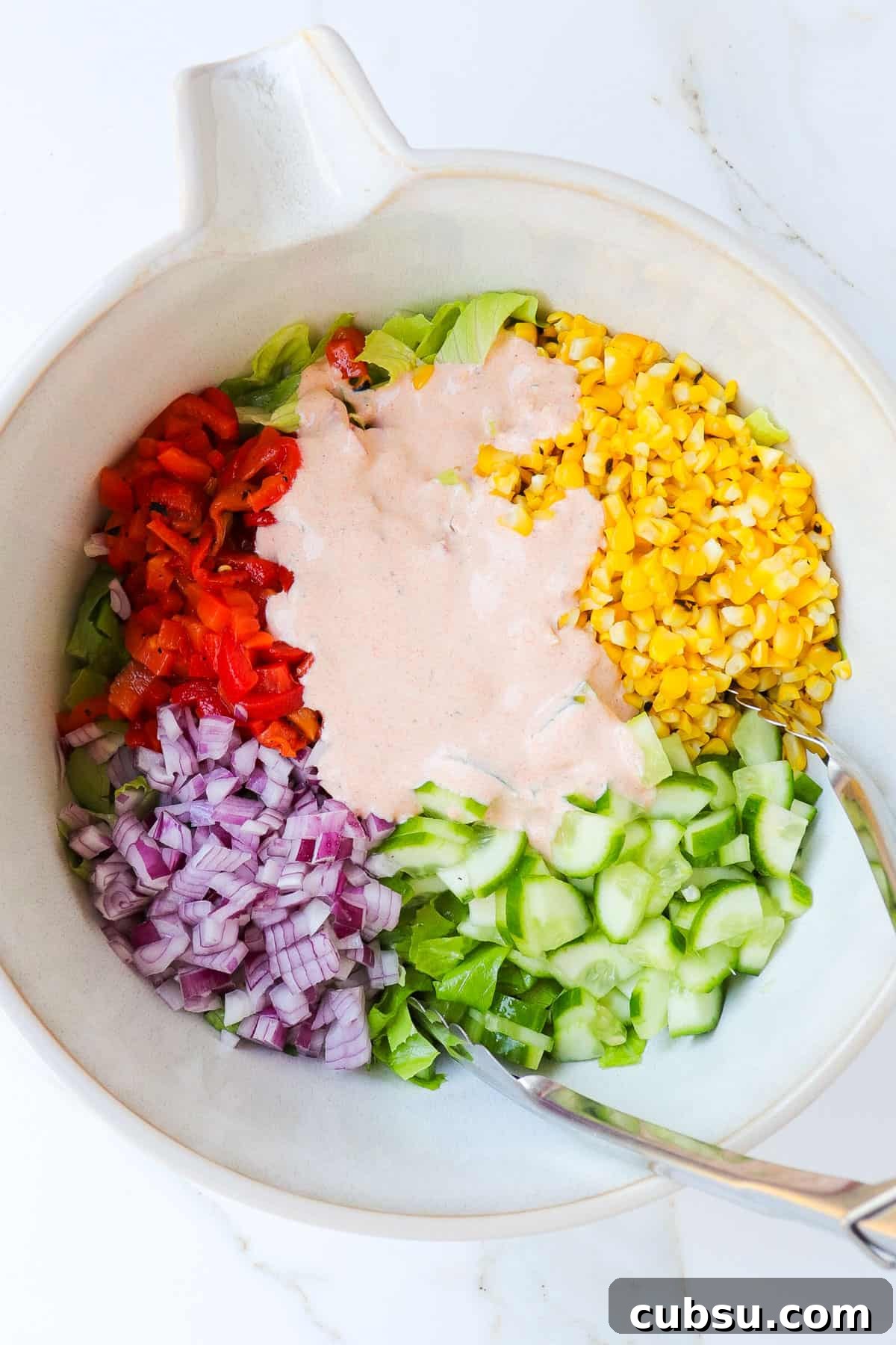 Zesty Cajun Shrimp Salad with Avocado and Lime Dressing 9 Salad ingredients in a bowl with tongs.