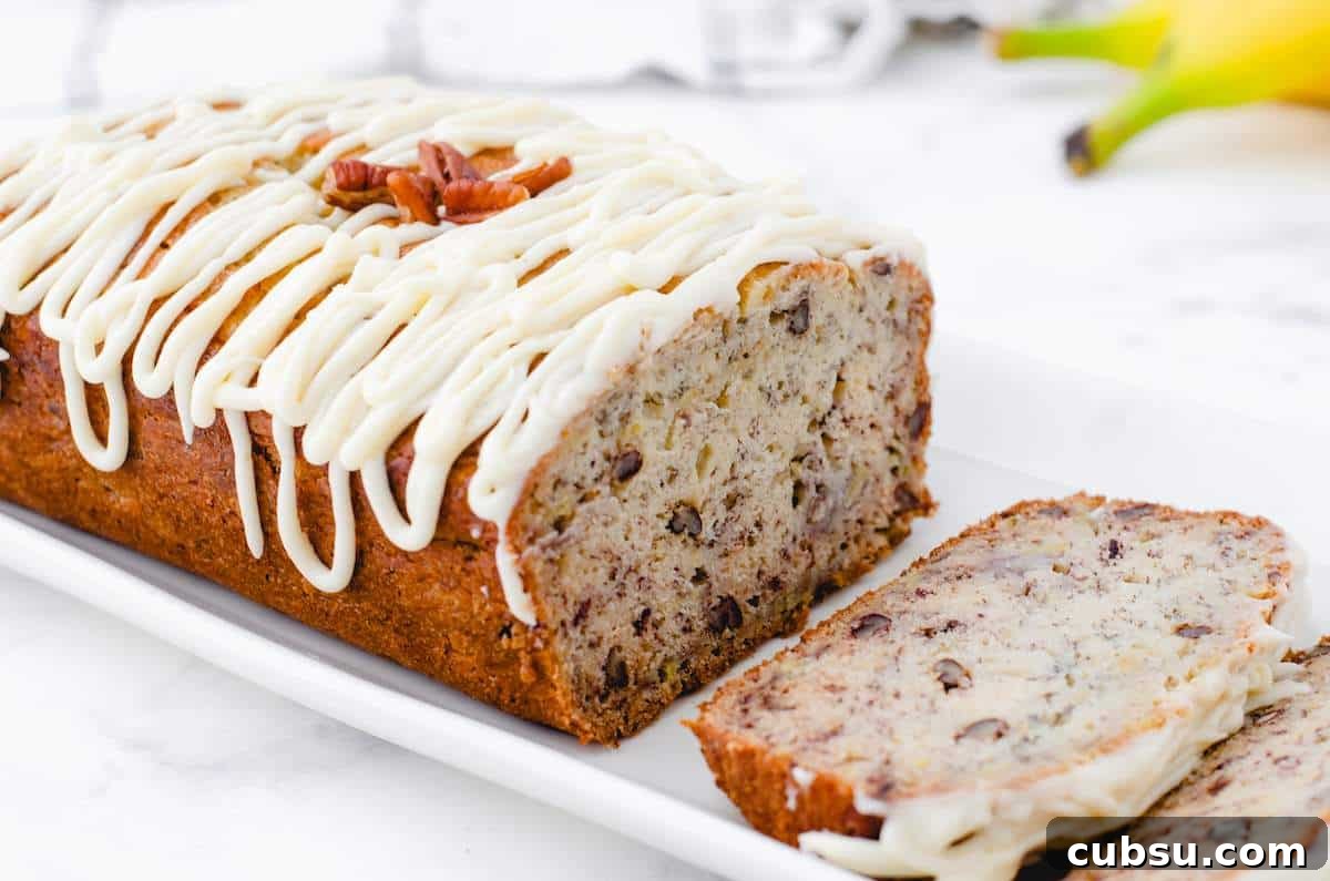 A loaf of sliced buttermilk banana bread with nuts with frosting drizzled on the top.