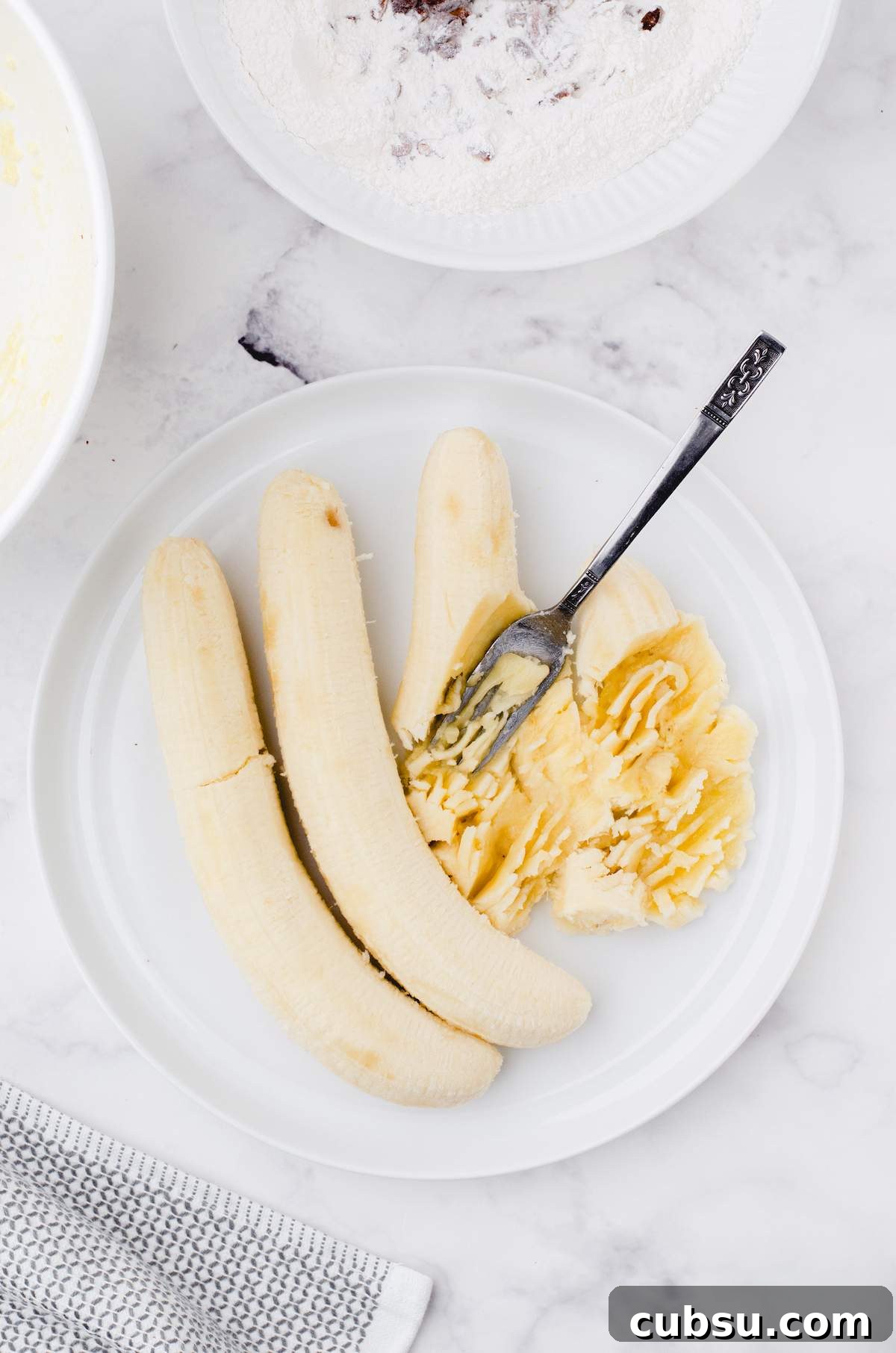 Mashed bananas on a plate for buttermilk banana bread.