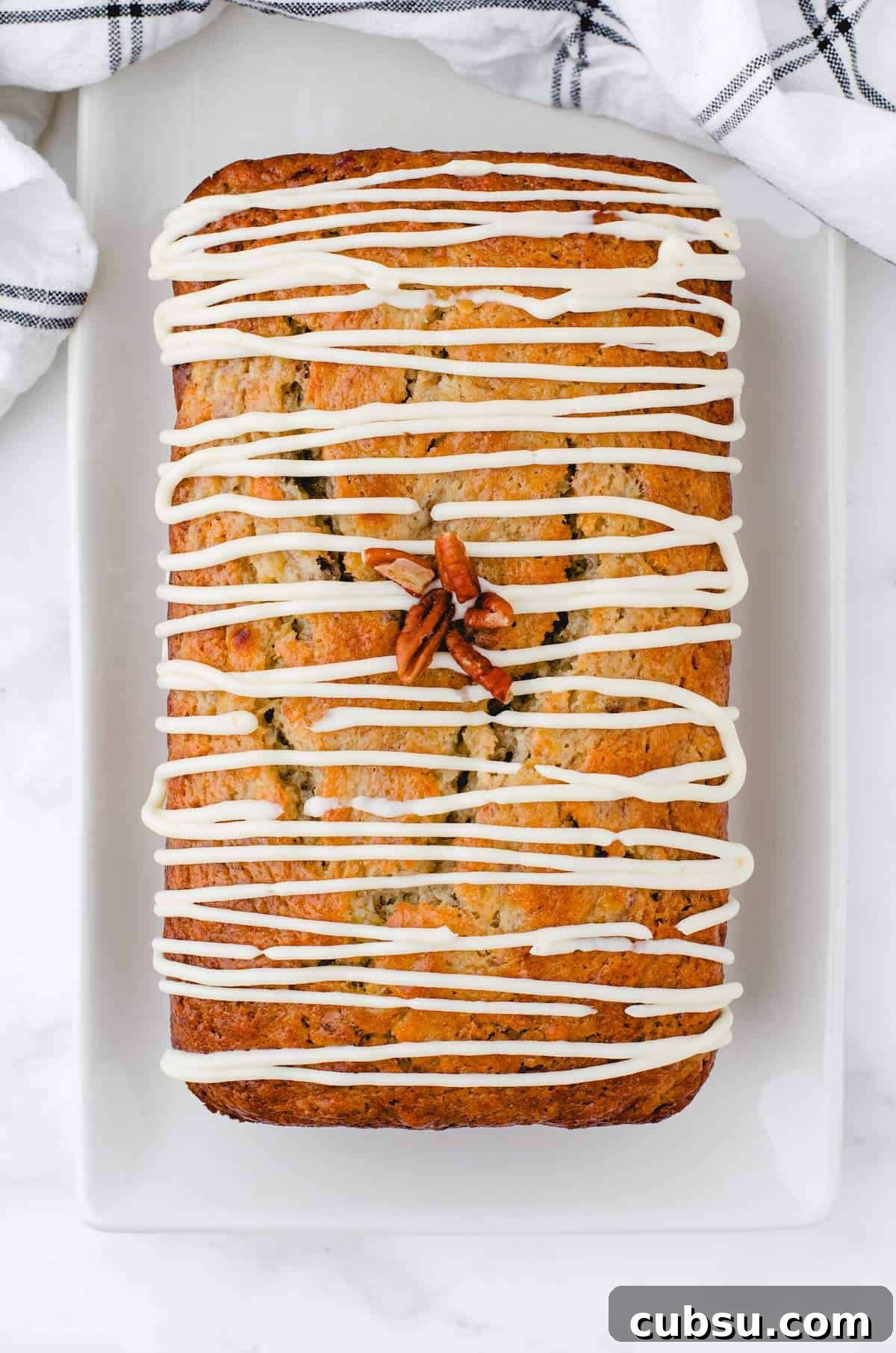 A loaf of buttermilk banana bread with Cream Cheese Frosting drizzled over the top.