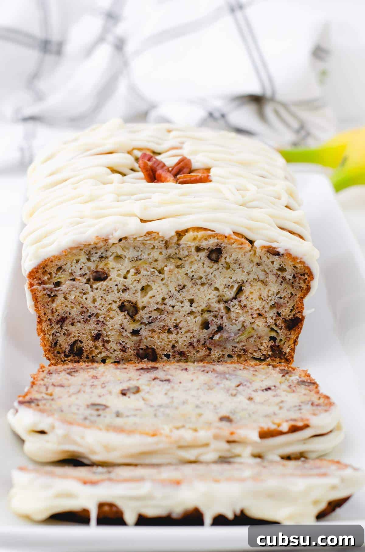 A cross section of buttermilk banana bread on a plate with cream cheese frosting on the top.
