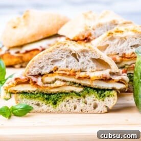 Crispy Chicken Parmesan Sandwich Recipe That Beats Takeout 9 Chicken Parmesan Sandwiches sliced and arranged on a cutting board, served with fresh basil and a rustic look.