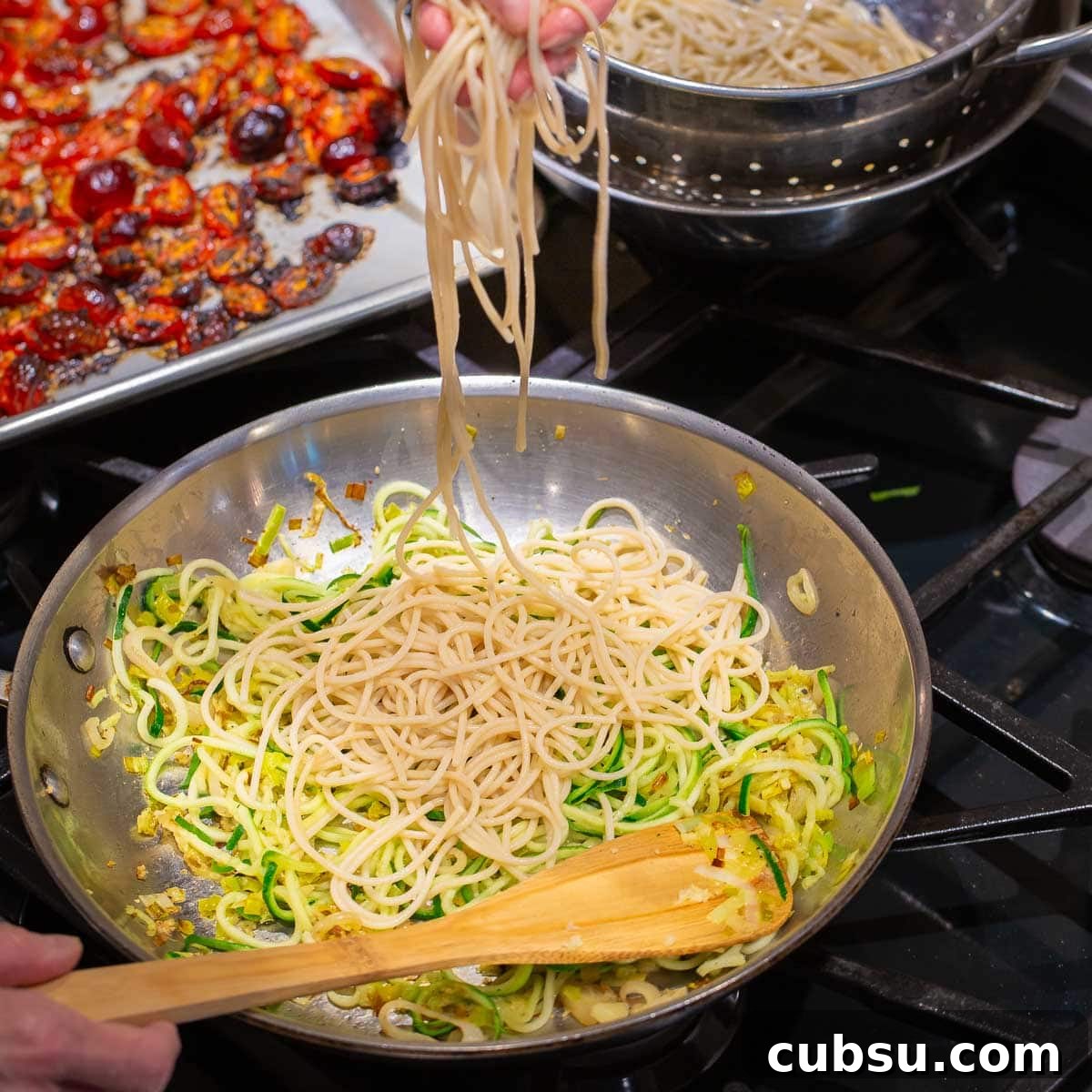 A pan of zucchini noodles and pasta with roasted red tomatoes. 