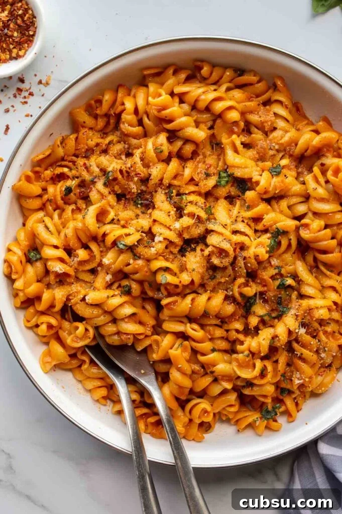 white pan with orange saucy pasta on a white background.