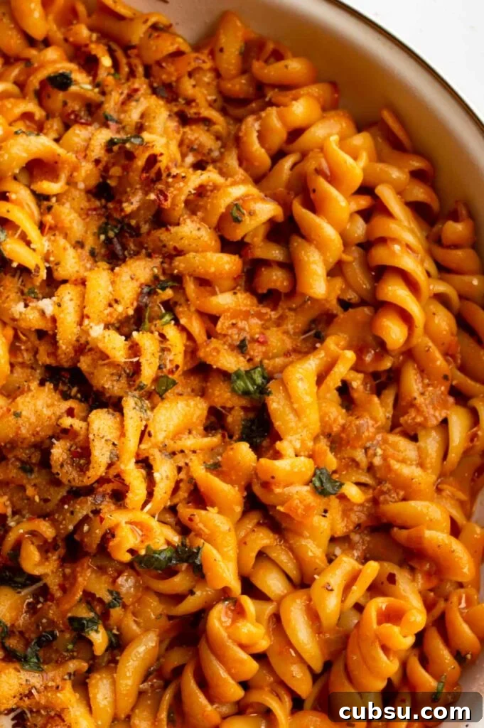 Closeup overhead of pasta coated in a creamy orange sauce.