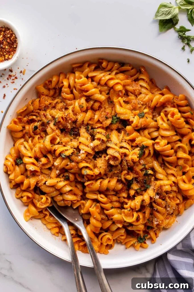 A white ceramic pan wit pasta in an orange creamy sauce.