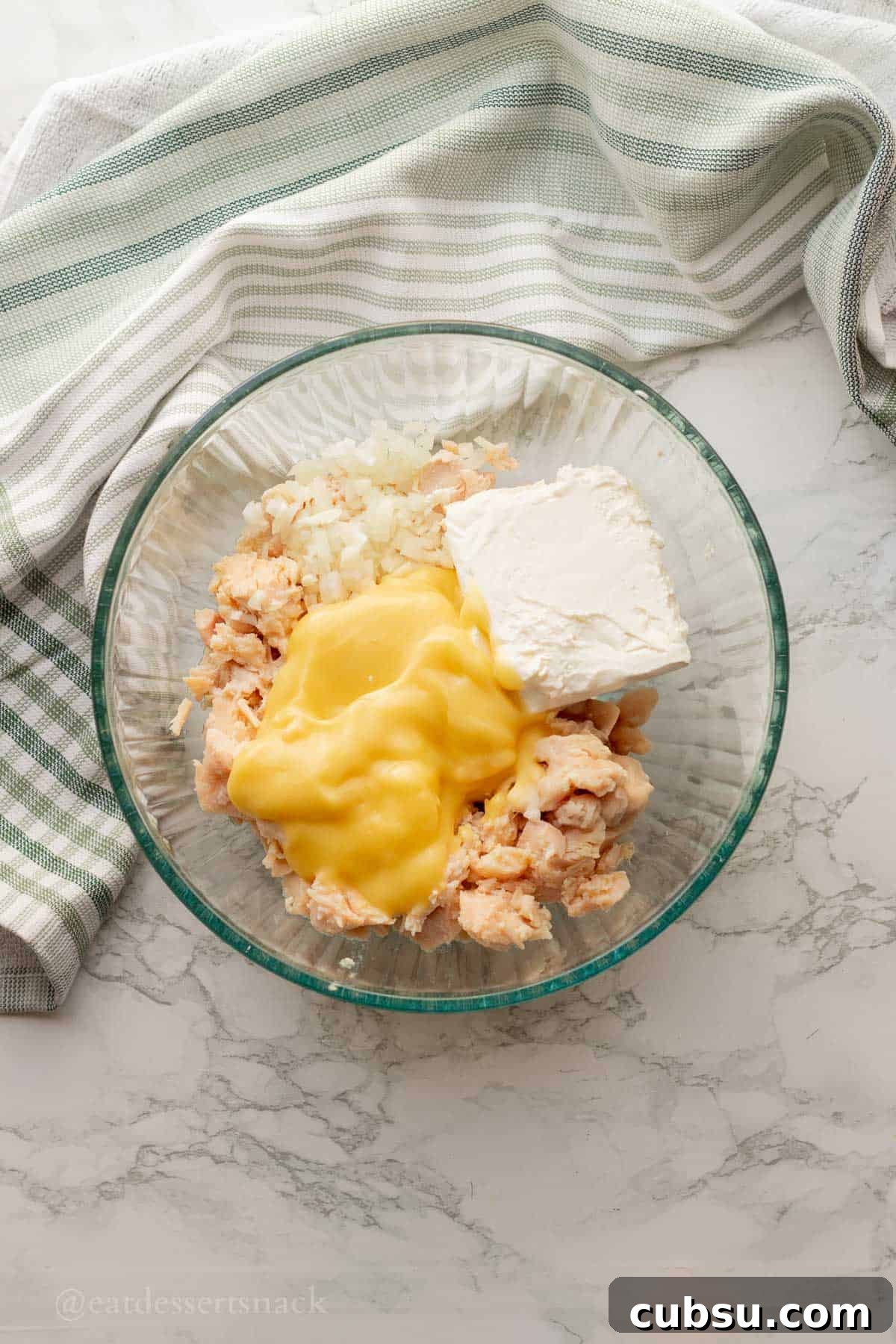 Cream cheese, chicken, onions, and cream of chicken soup in glass bowl.