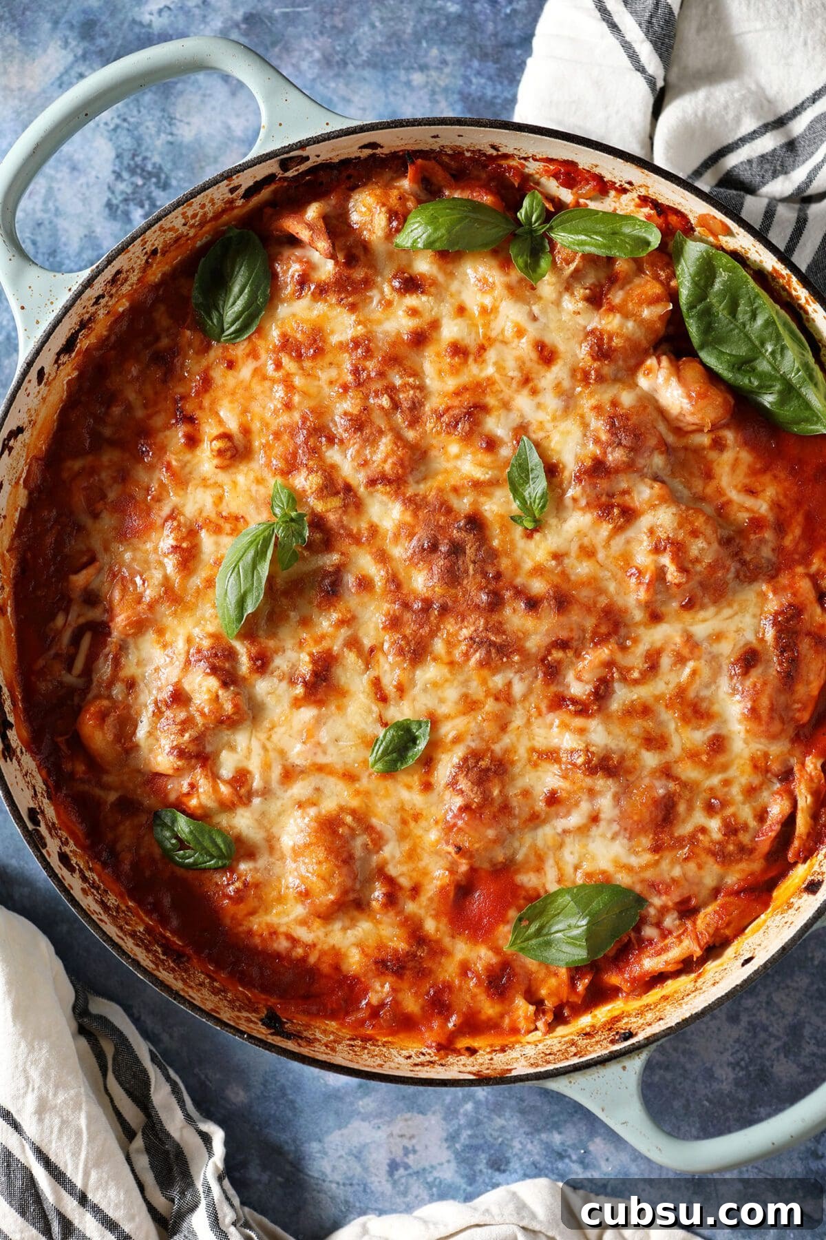 Baked Gnocchi with Chicken in a baking dish on a blue table garnished with fresh basil before serving