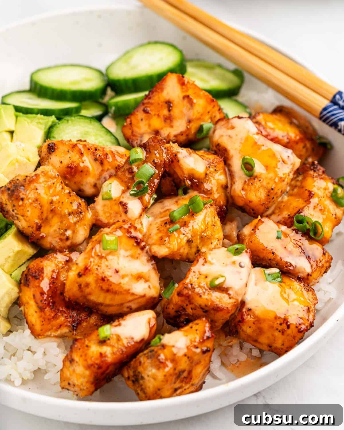 Close up of cubes of crispy air fryer salmon drizzled with spicy sauce.