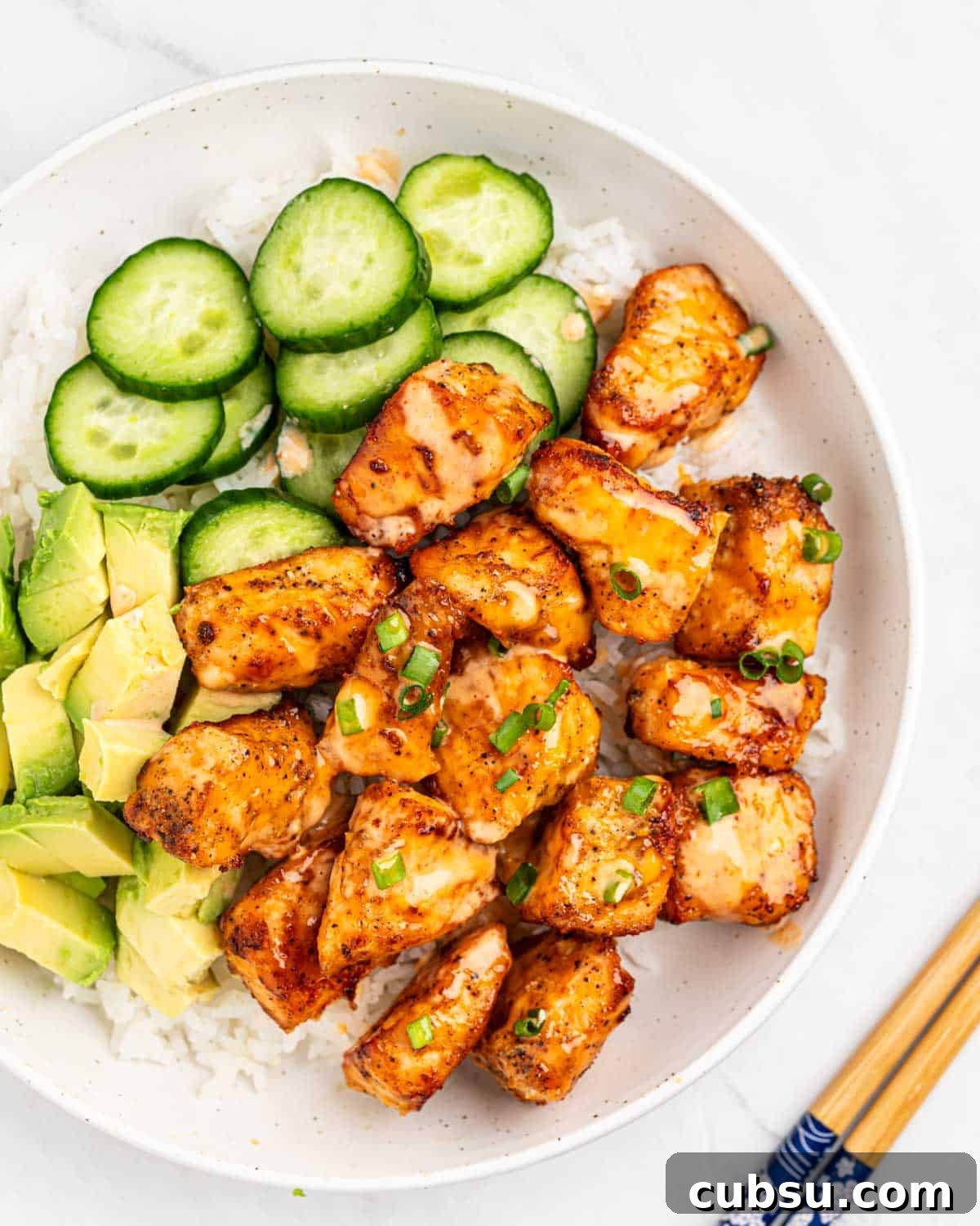 top down of plate of rice and air fryer salmon bites drizzled with sriracha mayo sauce.