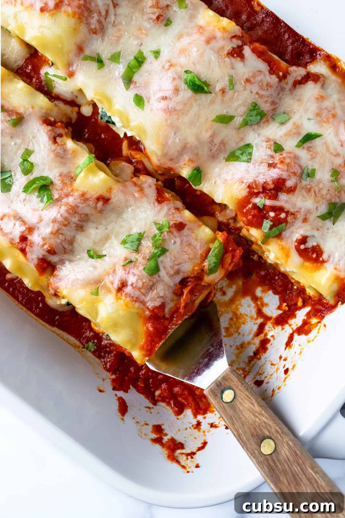 Cheesy Spinach Lasagna Rolls with Ricotta Filling 4 Vegetarian Lasagna Roll Ups in a baking dish with a spatula.